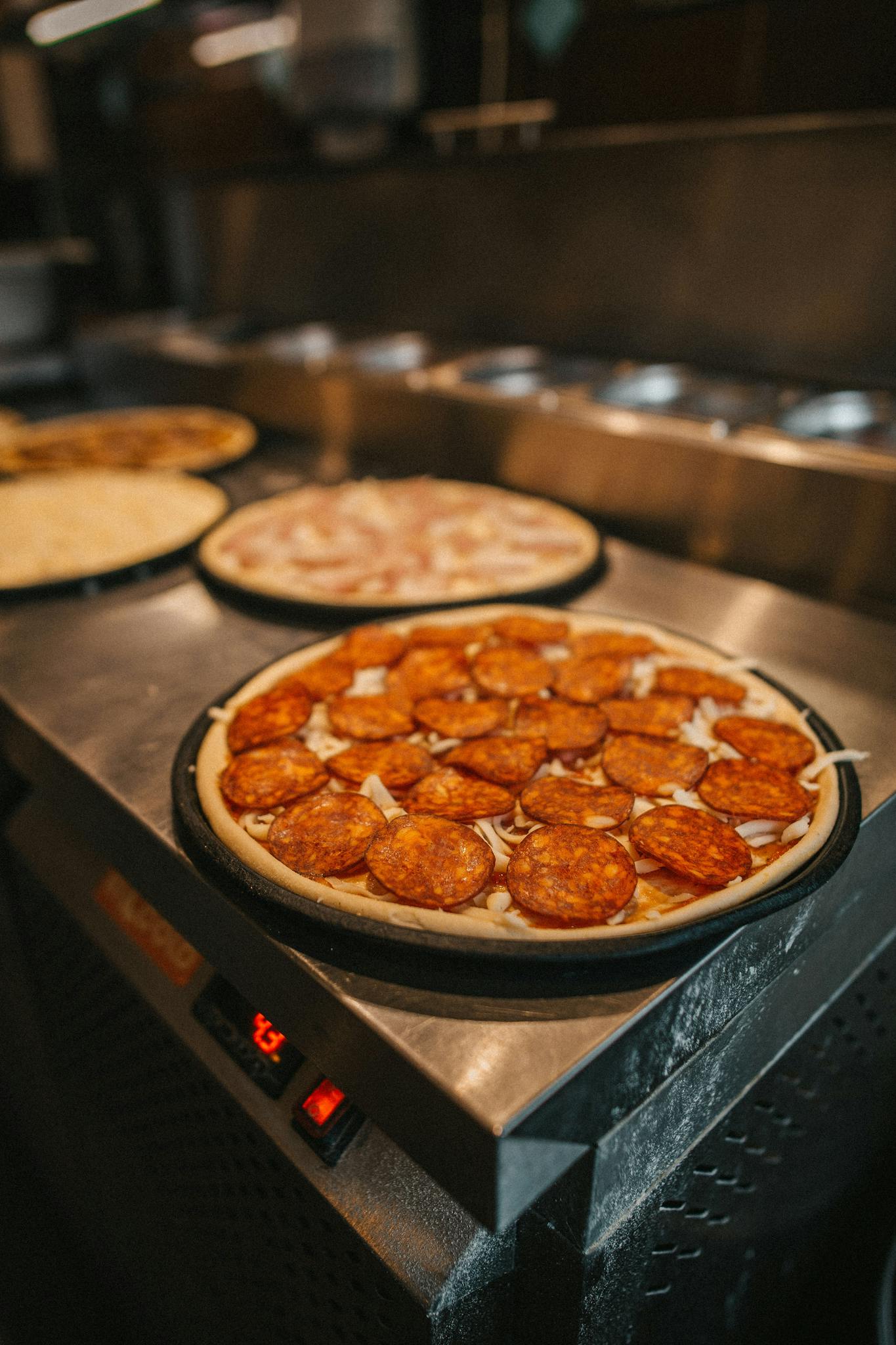Close-up of a pepperoni pizza ready to bake in a kitchen setting.